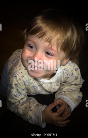 Peu cute smiling blonde boy posing in front of camera, portrait expressif Banque D'Images