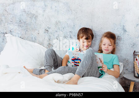 Belle fille est en train de lire un livre à son frère au lit Banque D'Images