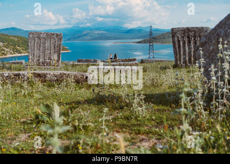 Deux jeunes filles s'asseoir à Sarajevo au lac, près d'une nécropole médiévale composé de pierres tombales, Stećak en Bosnie et Herzégovine Banque D'Images