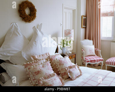 Couronne de rameaux au-dessus de lit avec oreillers blanc et rose +blanc coussins en toile de Jouy chambre blanche traditionnelle Banque D'Images