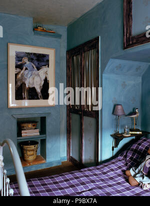 Grand tableau au-dessus de l'alcôve d'étagères dans la chambre de l'enfant bleu avec couvercle vérifié on bed Banque D'Images