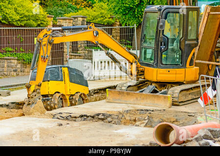 Drague orange sur les chantiers dans la ville. Construction d'égouts dans la région. Machines de travail en stationnement sur la route. Bulldozer sur place. Route abandonnée Banque D'Images