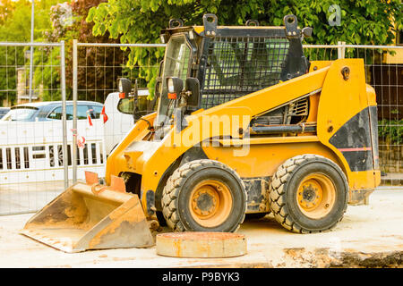 Drague orange sur les chantiers dans la ville. Construction d'égouts dans la région. Machines de travail en stationnement sur la route. Bulldozer sur place. Route abandonnée Banque D'Images