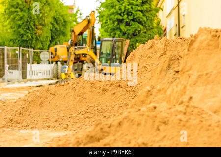 Drague orange sur les chantiers dans la ville. Construction d'égouts dans la région. Machines de travail en stationnement sur la route. Bulldozer sur place. Route abandonnée Banque D'Images