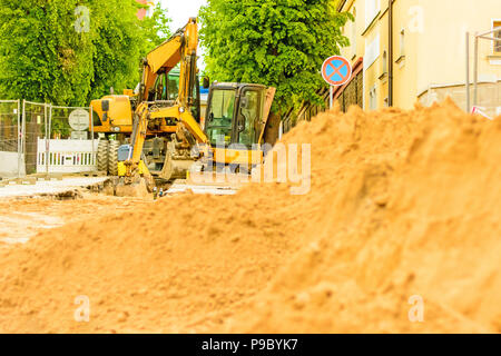 Drague orange sur les chantiers dans la ville. Construction d'égouts dans la région. Machines de travail en stationnement sur la route. Bulldozer sur place. Route abandonnée Banque D'Images