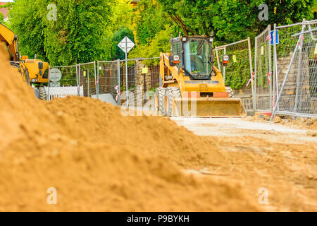 Drague orange sur les chantiers dans la ville. Construction d'égouts dans la région. Machines de travail en stationnement sur la route. Bulldozer sur place. Route abandonnée Banque D'Images