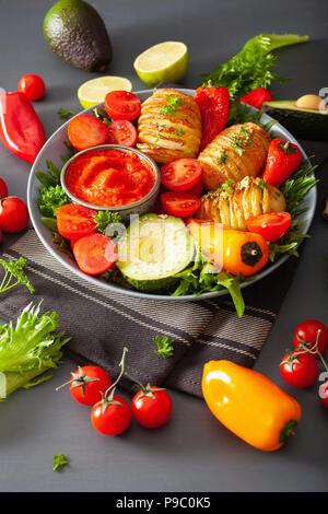 Bol bouddha vegan. dîner sain bol avec pommes de terre hasselback, avocat, tomate, poivrons et sauce au piment Banque D'Images