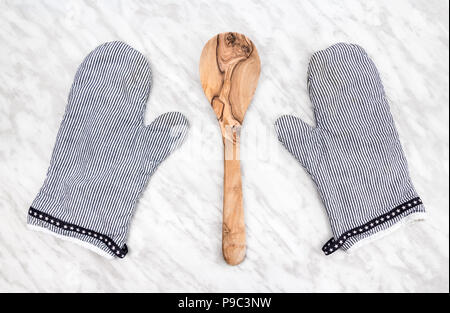 Cuillère en bois et le bar d'gants de cuisine, sur un comptoir en marbre. Banque D'Images