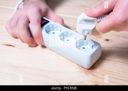 La main des hommes est tenue et la connexion d'un connecteur électrique sur une prise multiple Banque D'Images