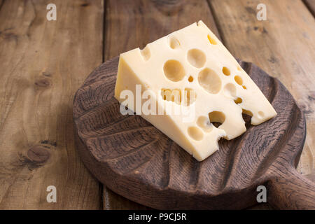 Fromage avec des trous sur une vieille planche en bois. Vintage photo. Les produits laitiers. Espace libre pour le texte. Copy space Banque D'Images