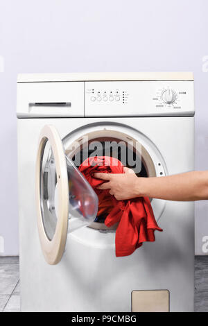 Les mains de l'homme mettre le linge dans une machine à laver. Home Appliances Banque D'Images