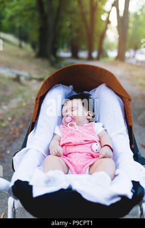 Magnifique petite fille dormir en plein air dans la poussette. Banque D'Images