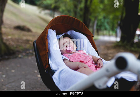 Magnifique petite fille dormir en plein air dans la poussette. Banque D'Images