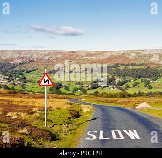 Avertissement panneau routier de matières dangereuses se penche en avant lente et peint sur la surface de la route, dans le Yorkshire Dales National Park, England, UK Banque D'Images