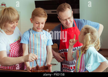 Heureux grands-parents de s'amuser avec leurs petits-enfants la préparation de muffins au chocolat à la cuisine moderne Banque D'Images