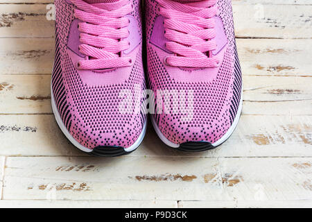 Sur la surface en bois est une paire de baskets avec lacets rose rose Banque D'Images