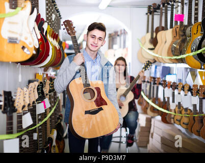 Les clients d'adolescent russe positive décider sur guitare acoustique approprié dans guitar shop Banque D'Images