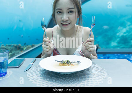 Belle femme asiatique dîner le monde sous-marin, sous-marin de fond restaurants dans les Maldives. Banque D'Images