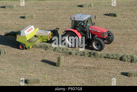 Agriculteur de Swaledale, Yorkshire du Nord La réalisation de balles de foin, à l'aide d'un et un Massey Ferguson 5470 Claas ramasseuse-presse. Banque D'Images