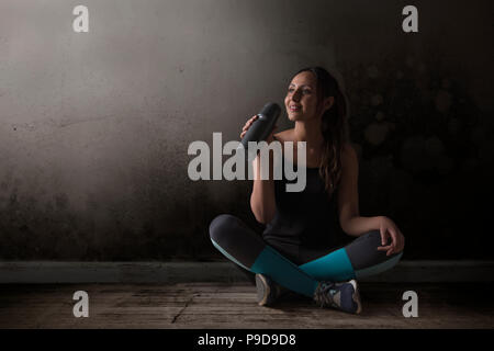 L'eau potable coureuse assis les jambes croisées sur le plancher Banque D'Images