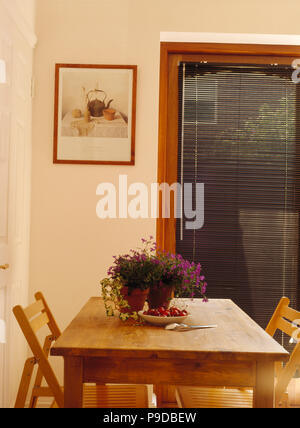 Chaises en bois pliantes à table en pin de style économique en salle à manger avec fenêtre sur le store vénitien noir Banque D'Images