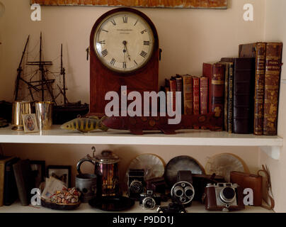 Horloge ancienne et vieux livres reliés en cuir sur des étagères avec des vieux appareils photos Banque D'Images