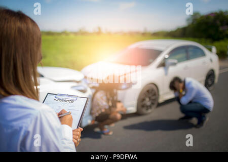 Agent d'assurance, writing on clipboard après accident de voitures. Banque D'Images