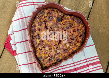 Un clafouti aux cerises sous la forme de cœur sur une table en bois Banque D'Images