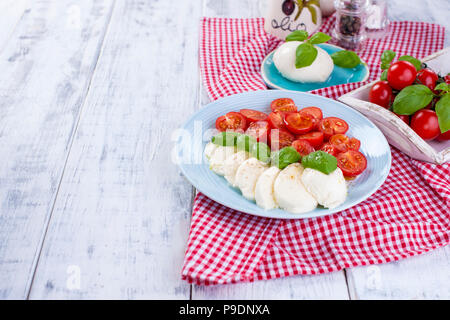 Salade caprese italien avec. Salade composée de légumes et de fromage. Vaisselle en céramique. Espace libre pour le texte. Sèche-serviettes dans une cage rouge Banque D'Images