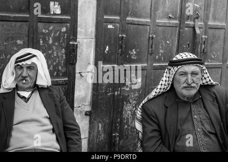 Deux hommes sont assis palestiniens ayant un chat un zigarettes dans la vieille partie de la ville d'Hébron et qui portent des colonies illégales par la puissance occupante Isra Banque D'Images