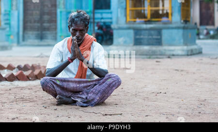 PUDUCHERY, Pondichéry, Tami Nadu, Inde - septembre vers 2017. Un homme non identifié est assis les jambes croisées et les mains de méditer devant un hindu Banque D'Images