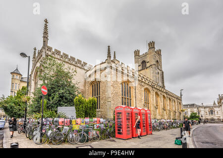 Une femme pose en face de quatre cabines téléphoniques rouges à l'extérieur de l'édifice de grand St Mary, l'église de l'université de Cambridge, Angleterre. Banque D'Images