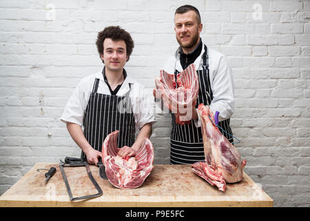 Deux bouchers côte à côte, les articulations de la viande maintenant partie d'une grande carcasse massacrée. Banque D'Images