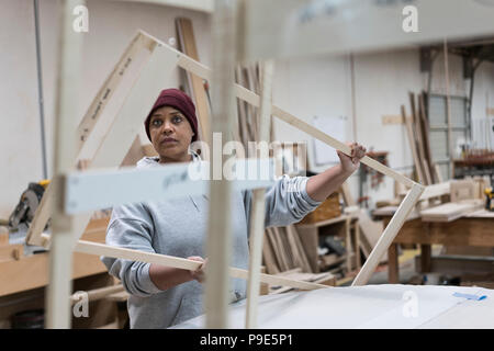 Une femme noire menuisier travaillant sur un projet du cabinet à un grand atelier de menuiserie. Banque D'Images