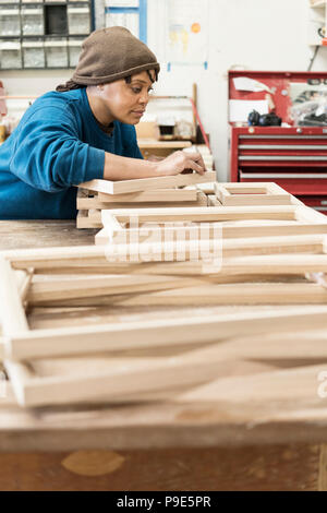 Une femme noire menuisier travaillant sur un projet du cabinet à un grand atelier de menuiserie. Banque D'Images