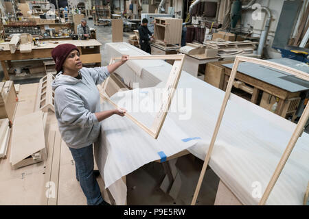 Une femme noire menuisier travaillant sur un projet du cabinet à un grand atelier de menuiserie. Banque D'Images