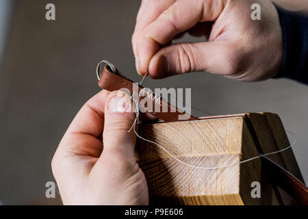 Close up of artisan cuir brun en bandoulière, couture main deux pièces de cuir, tenue dans un collier. Banque D'Images