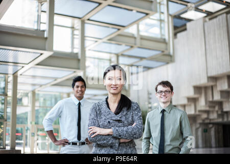 Le portrait d'une équipe de course mixte d'hommes d'affaires debout dans le hall d'un centre de convention avec une Asiatique businesswoman en tête. Banque D'Images