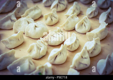 Boulettes crues chinois placé sur planche de bois. S'appelle dumplings jiaozi en chinois, est une populaire de la cuisine chinoise traditionnelle. Banque D'Images