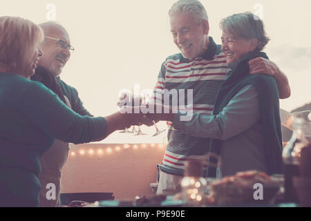 Groupe de personnes adultes senior en activité de loisirs faire un barbecue barbecue sur le toit-terrasse de la maison avec vue sur la montagne. repas et du vin pour deux hommes et deux Banque D'Images