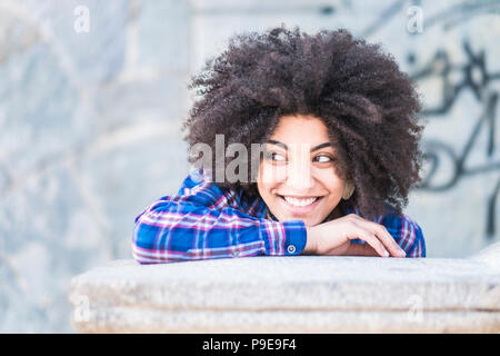 Portrait de race africaine de la peau noire de belle jeune fille souriant et à la recherche à ses côtés. Profitant de l'heure et l'activité de loisirs. Ambiance décontractée et fa Banque D'Images