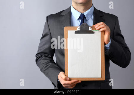Jeune homme debout avec dossier, isolé sur fond gris Banque D'Images