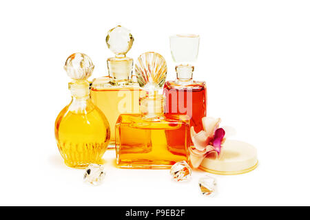 Le groupe des Flacons à parfum vintage avec les bouchons en verre, d'un cosmétique en poudre dans la boîte en plastique blanc et fleurs artificielles isolated on white Banque D'Images