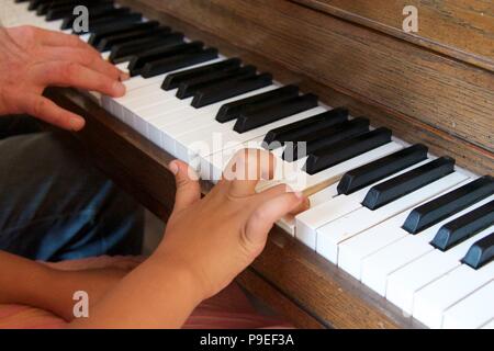 Leçon de piano : un des profils essaie d'encourager un enfant au piano par exemple Banque D'Images