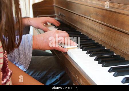 Leçon de piano : un des profils essaie d'encourager un enfant au piano par exemple Banque D'Images