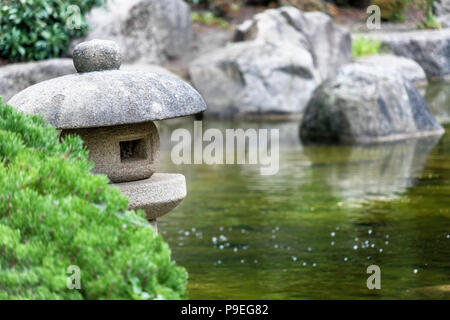 Étang dans un jardin japonais avec une lanterne de pierre traditionnelle à l'avant-plan, la faible profondeur de champ Banque D'Images