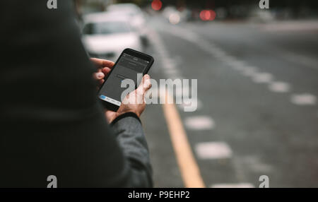 Close up of mature man en utilisant le covoiturage application sur smartphone pour la commande de taxi on city street. Banque D'Images