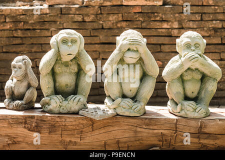 Trois Singes de la sagesse et un quatrième se gratte la tête de singe en Wat Umong, Chiang Mai, Thaïlande Banque D'Images