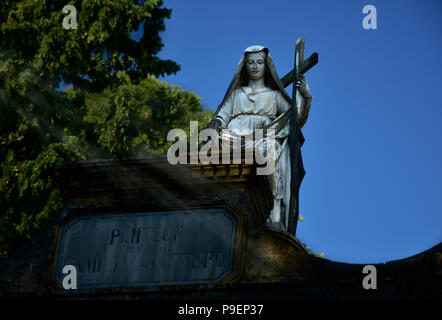 Des statues dans le cimetière. Vierge portant une croix dans la partie supérieure d'un tombeau. Banque D'Images