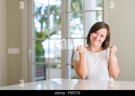 Le syndrome de femme à la maison très heureux et excité de faire geste gagnant avec bras levés, souriant et criant pour la réussite. Concept de célébration. Banque D'Images